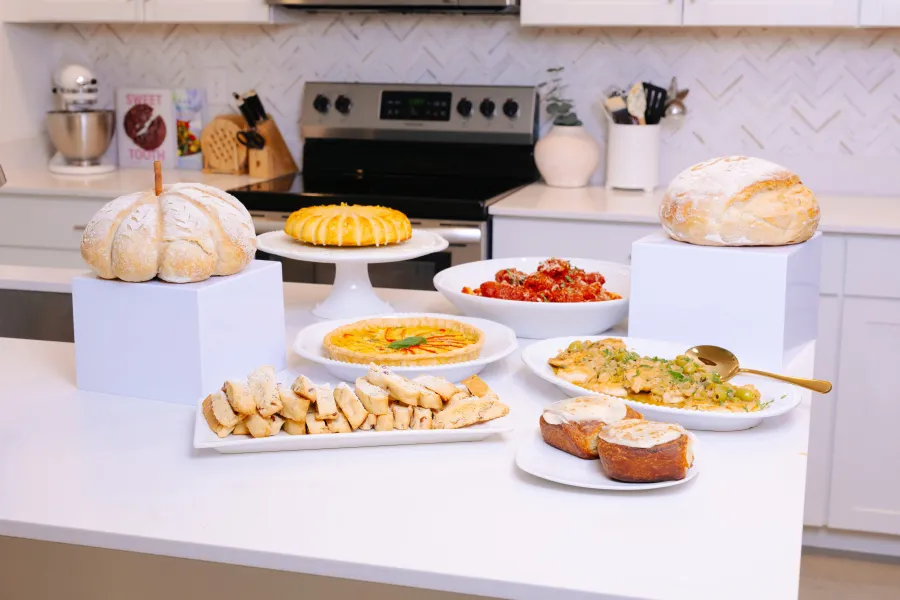 Woman standing beside a table filled with homemade Italian dishes
